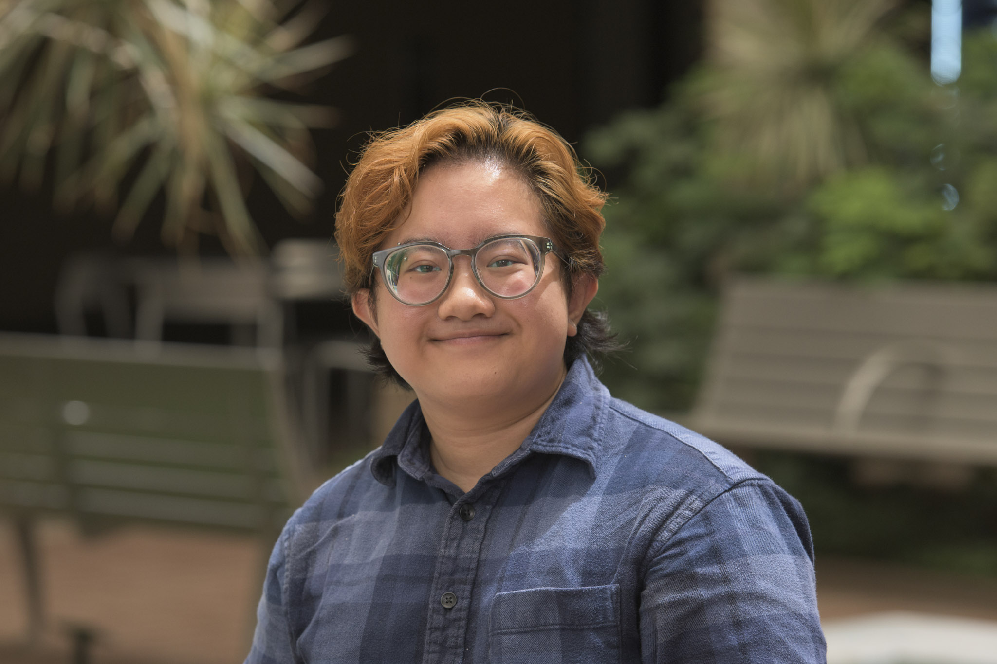 alt text: person with glasses and orange/black hair smiles at the camera